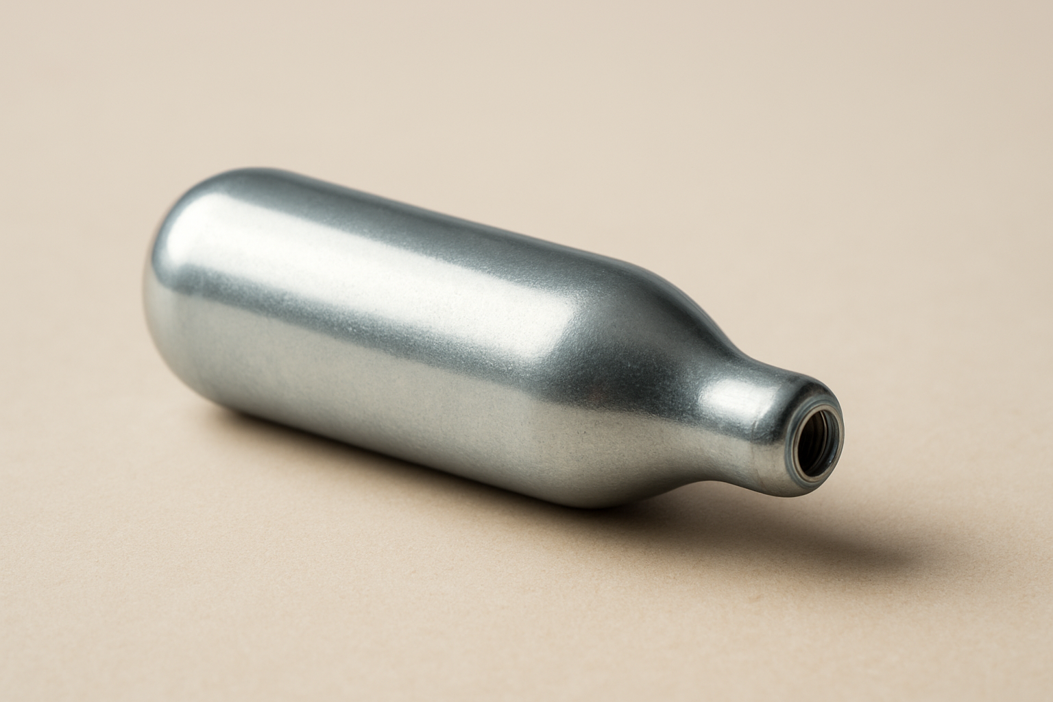 A close-up of a silver nang canister on a neutral background
